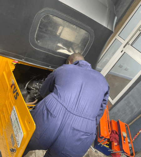 Mechanic working on the inside of a yellow tricycle